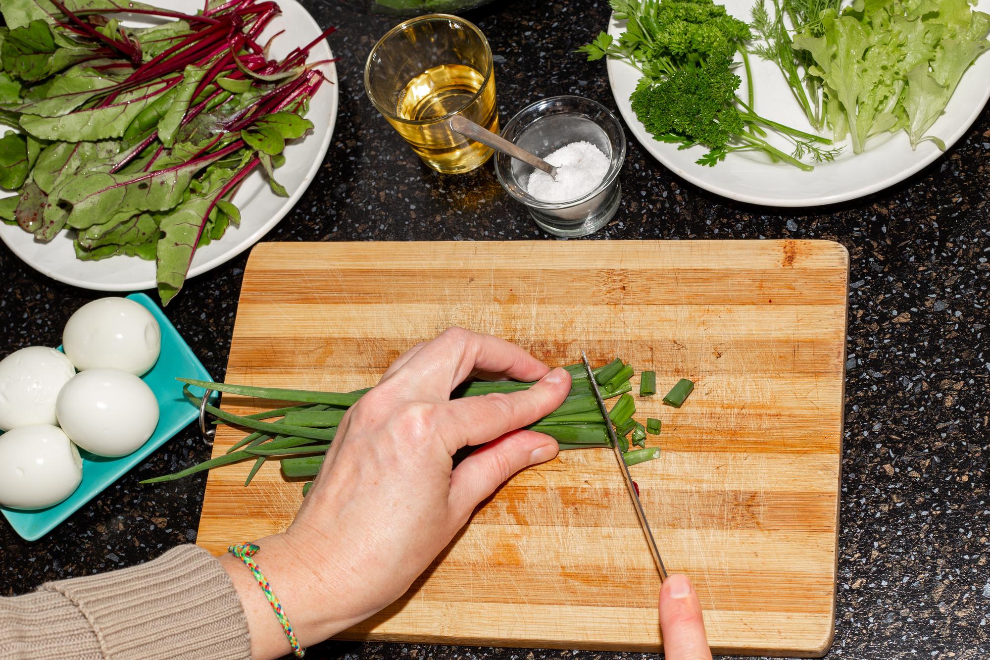 hands chopping herbs on a wooden board